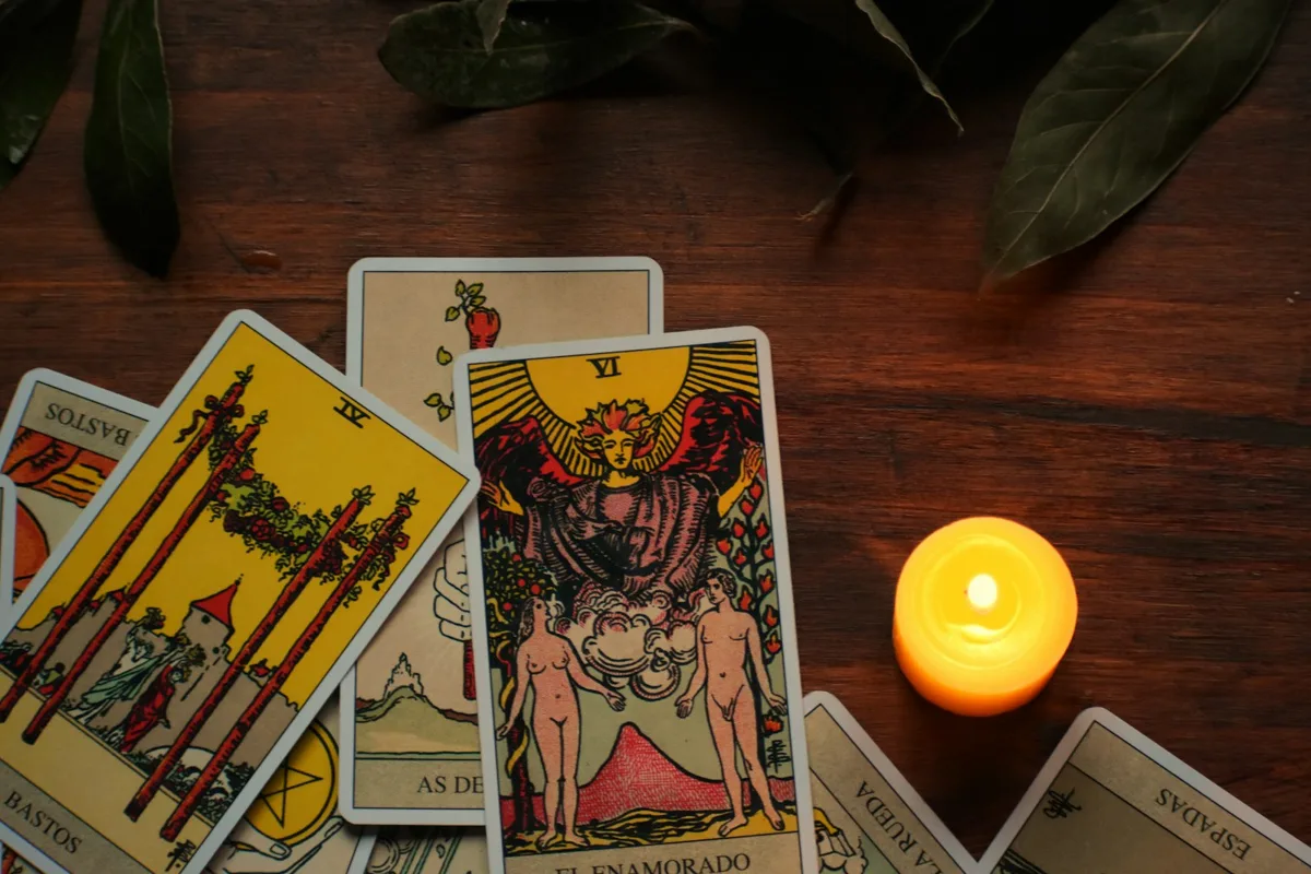 Cartas de Tarot tradicionales y una vela encendida sobre una mesa de madera.